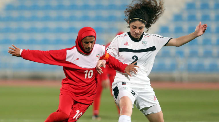 東京オリンピックの女子サッカー予選でパレスチナ代表選手と競り合うイラン代表選手